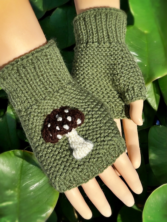 Knitted mushroom-themed fingerless gloves styled with autumn leaves and natural woodland elements."