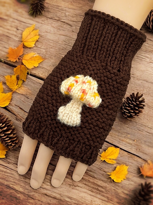 Knitted mushroom-themed fingerless gloves styled with autumn leaves and natural woodland elements."