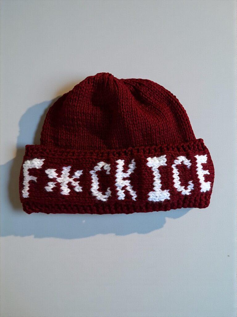 and-knit beanie with bold colorwork text reading ‘F*ck ICE + Trump.’ Free knitting pattern.