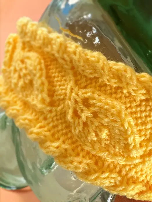 Close up of textured leaf motif on knit flat headband pattern using straight needles for cozy winter ear warmer