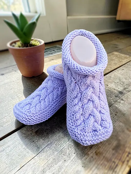 Cable slipper knitting pattern showing finished handmade slippers with a warm textured design