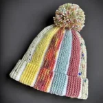 Free knitting pattern Scrap Beanie showing bobble beanie style knit flat with scrap yarn and textured colour sections