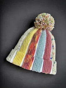 Free knitting pattern Scrap Beanie showing bobble beanie style knit flat with scrap yarn and textured colour sections