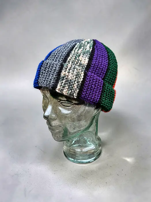 Fisherman style Scrap Beanie free knitting pattern displayed on glass head with folded brim and bobble texture
