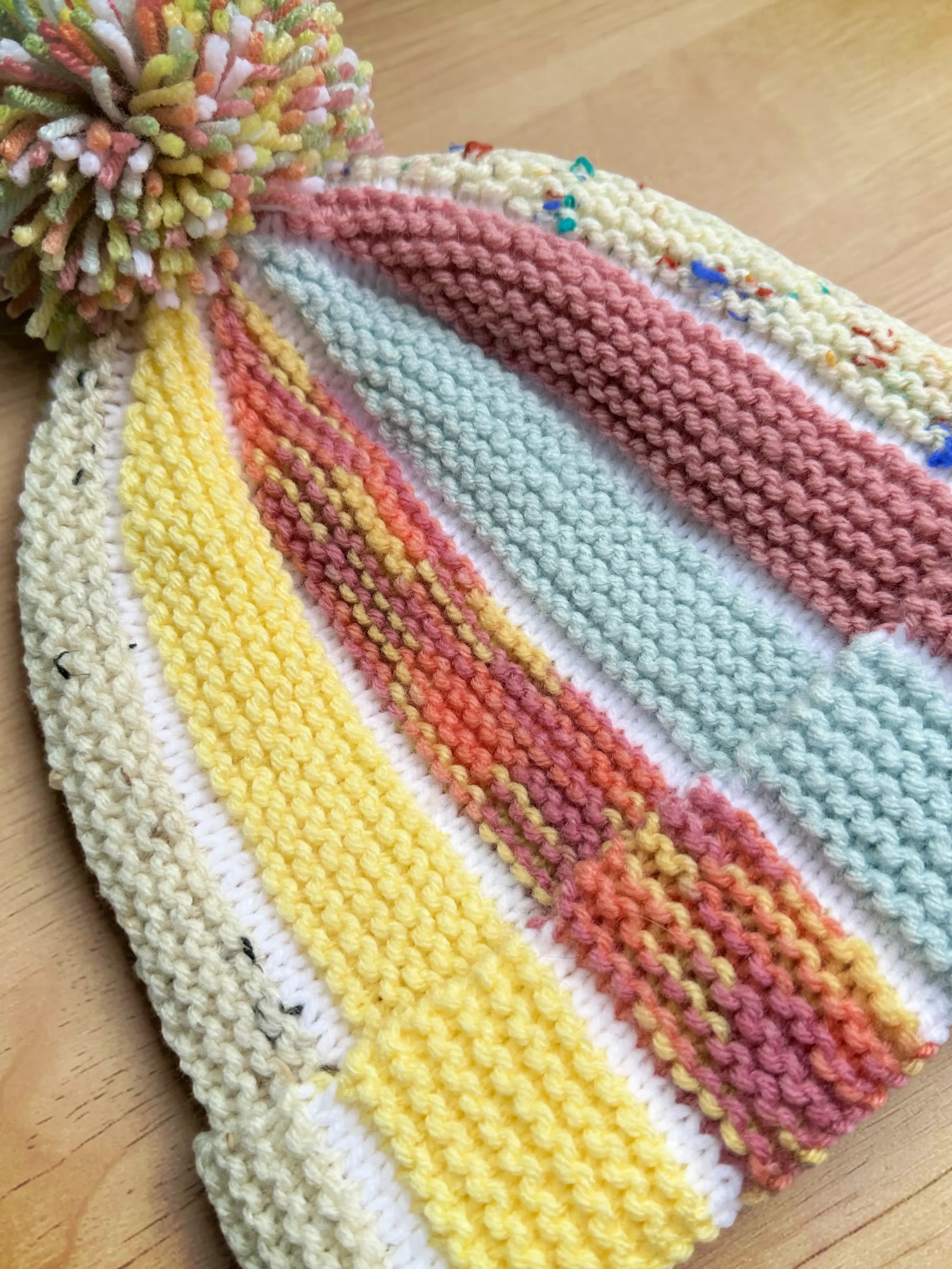 Free knitting pattern Scrap Beanie showing bobble beanie style knit flat with scrap yarn and textured colour sections