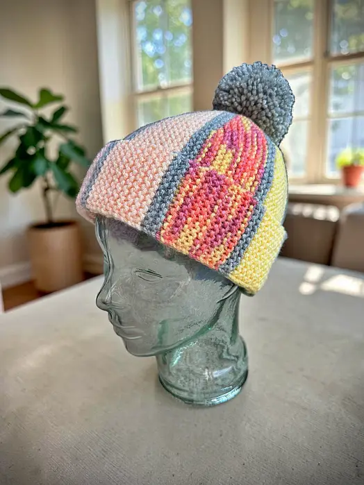 Mosaic scrap yarn beanie on a glass mannequin head, free knitting pattern
