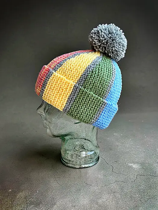 Scrap yarn beanie knitting pattern shown on a glass mannequin head